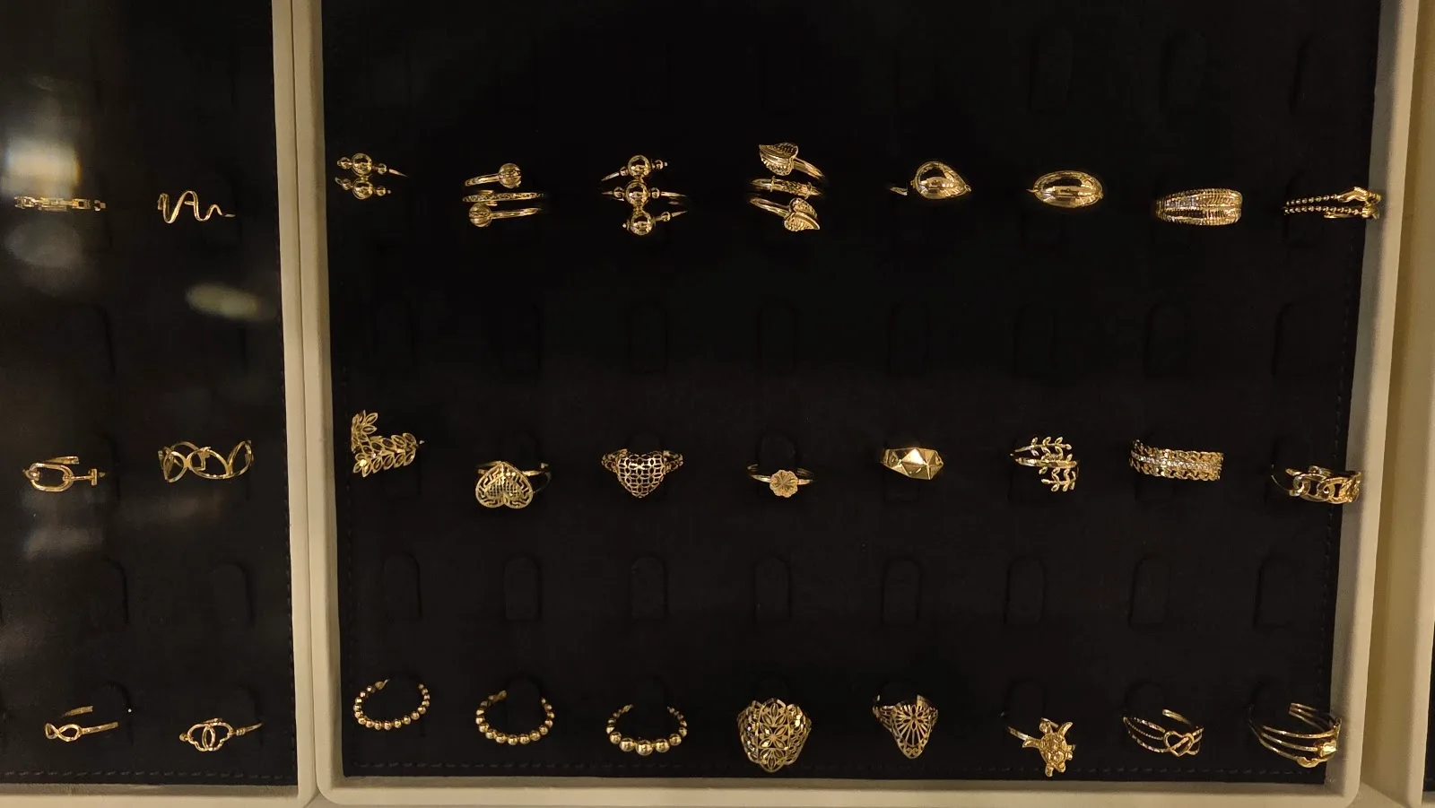 Gold rings arranged on a black velvet tray at Top Pure Jewellery