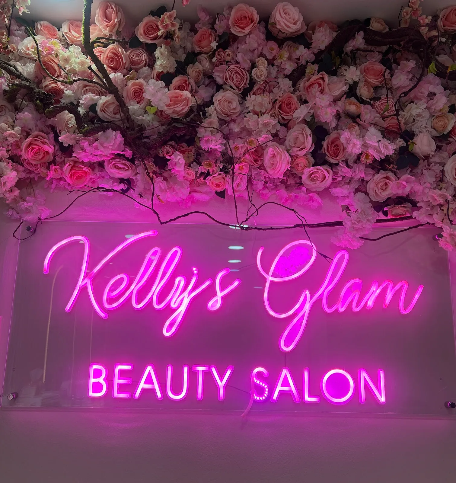 Kelly's Glam Beauty Salon pink neon sign beneath a wall of roses inside the Al Satwa studio