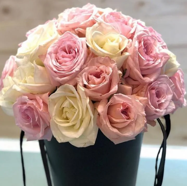 Blush and cream roses arranged in a black hatbox