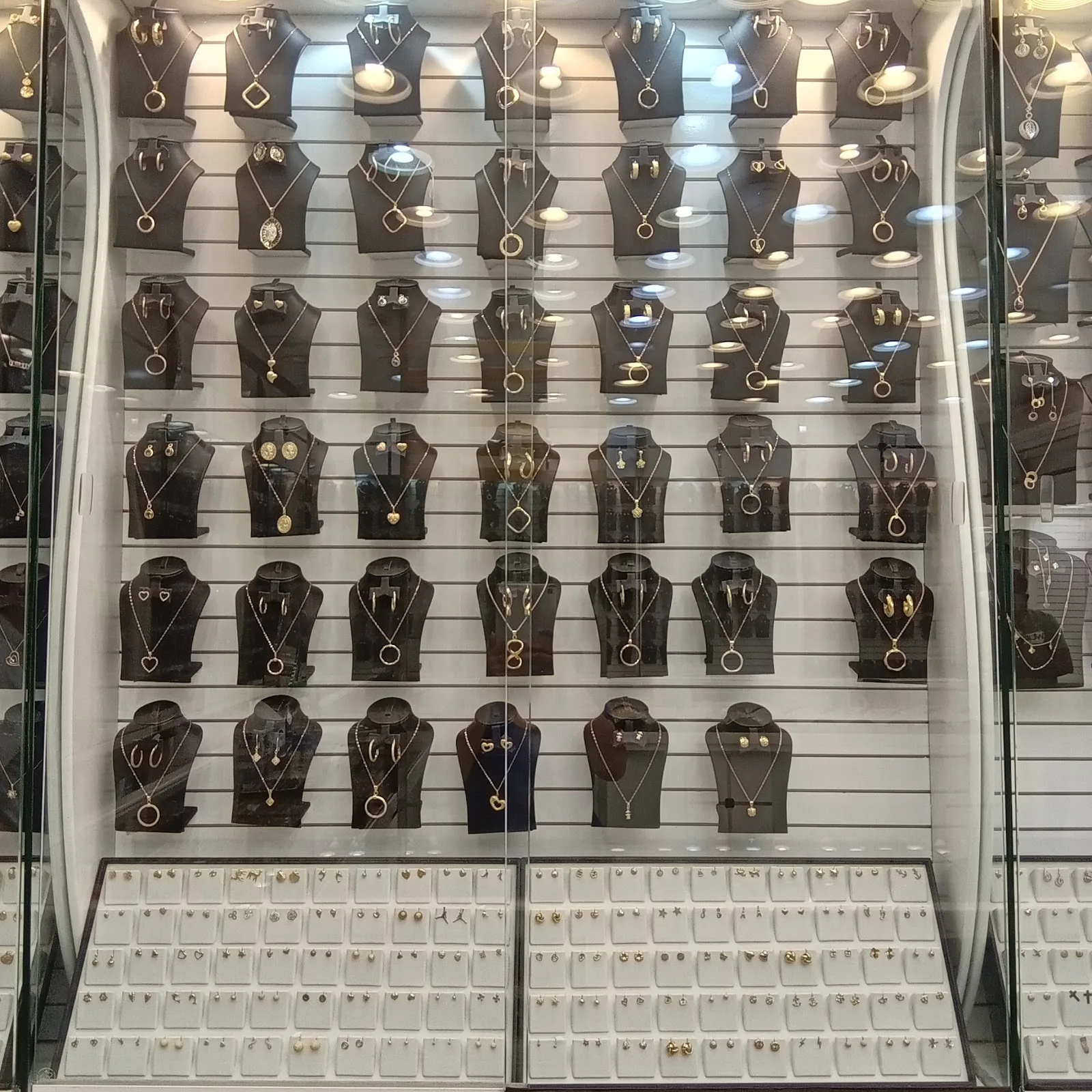 Display wall of gold necklaces, pendants and earrings behind glass at Eskandar Barakat Jewellery